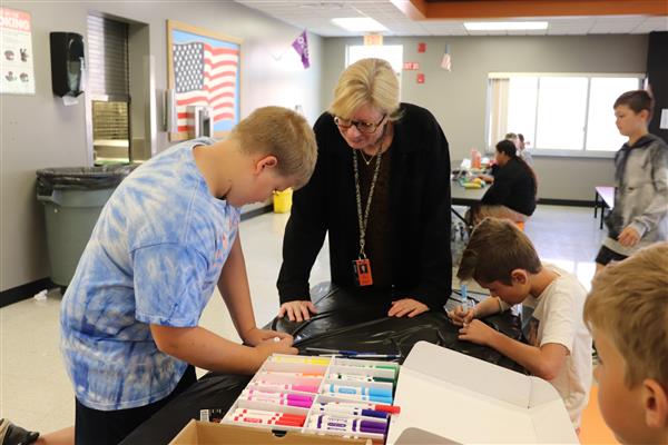 Student coloring puzzle piece with Ms. Mann looking on