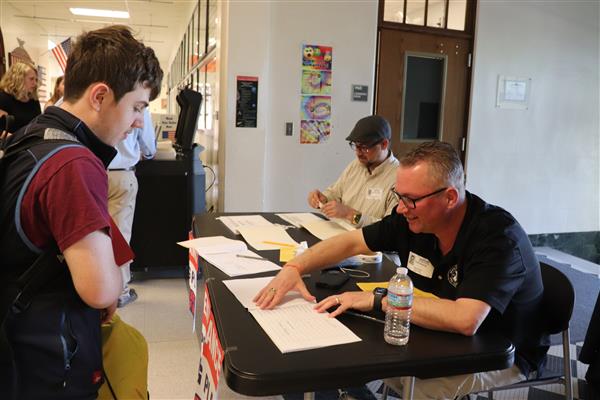 Mr. Rooney shows student where to sign for ballot